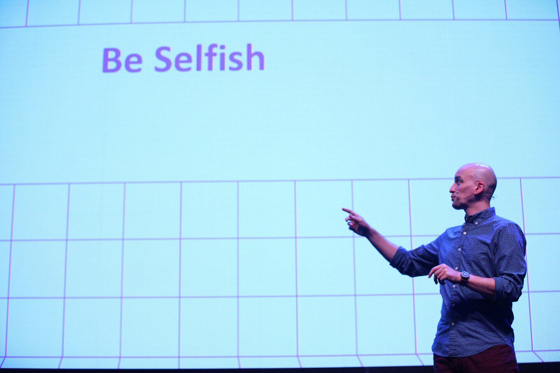 Adrian pointing at the text “Be selfish” on his slide.